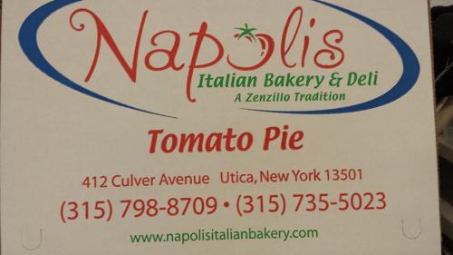 A pizza box from Napoli's Italian Bakery & Deli, featuring "Tomato Pie" and contact information in Utica, New York.