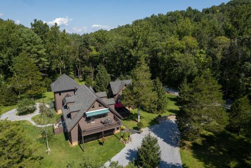 Aerial view of a large wooden cabin surrounded by lush green trees and a gravel path.