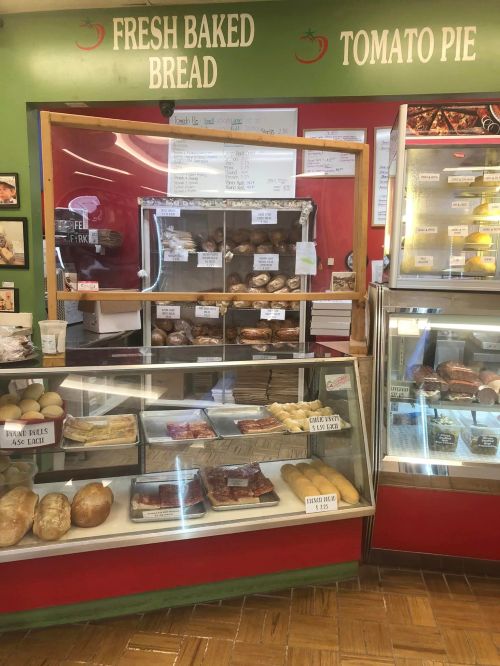A bakery display featuring fresh baked bread, tomato pie, and various pastries behind glass counters.