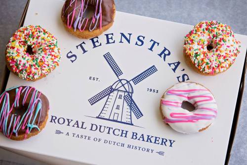 A box from Steenstra's Royal Dutch Bakery with colorful donuts on top, featuring sprinkles and icing.