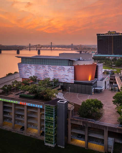 Aerial view of the Muhammad Ali Center at sunset, with a river and bridge in the background.