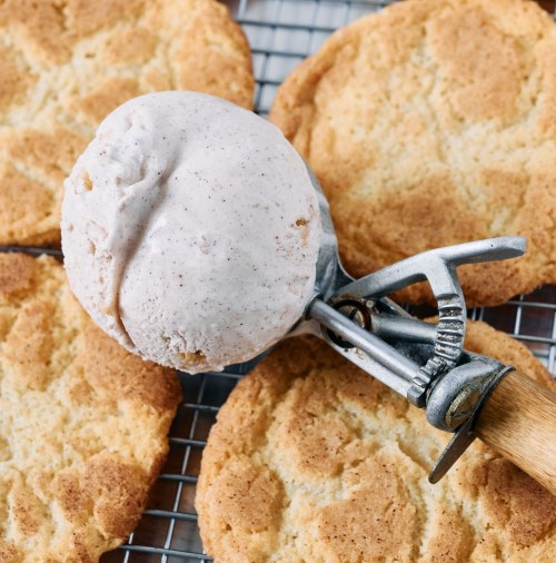 A scoop of cinnamon ice cream on a wire rack with freshly baked cookies.