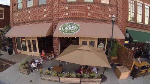 Outdoor seating area of Label Restaurant, featuring umbrellas and patrons enjoying their meals in a brick building setting.