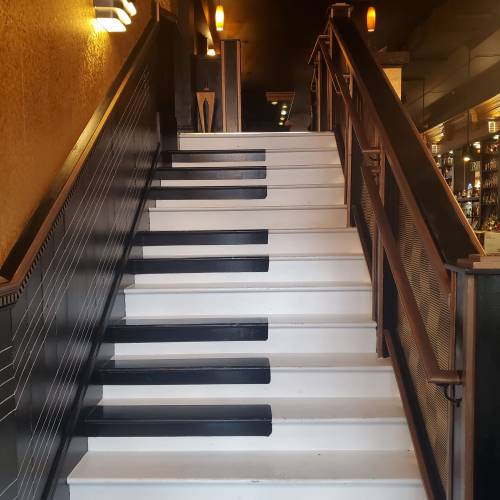 Staircase designed to resemble a piano keyboard, with black and white steps leading upward.