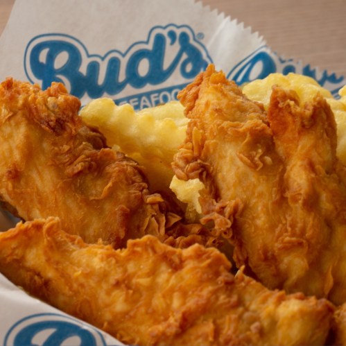 Crispy golden fried fish fillets served with a side of fluffy fries on a paper-lined plate.