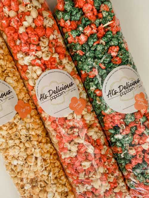 Three colorful bags of popcorn: yellow, red, and green varieties, labeled "Al's Delicious Popcorn."