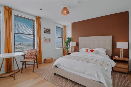 Bright bedroom with a large bed, wooden furniture, and large windows featuring orange curtains and a cozy atmosphere.