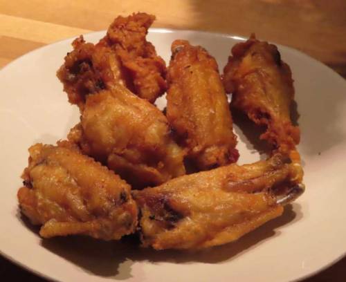 A plate of crispy, golden-brown fried chicken wings arranged neatly.