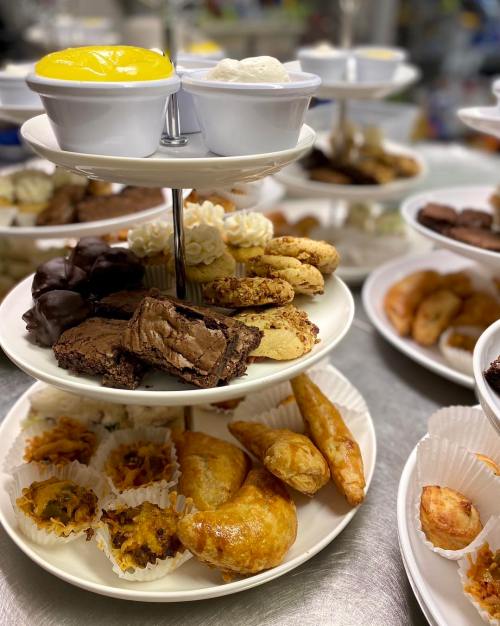 A tiered dessert stand filled with various pastries, cookies, brownies, and a cup of yellow custard on top.