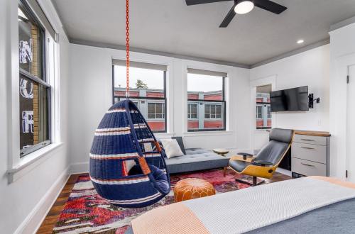 Cozy room featuring a hanging chair, modern furniture, large windows, and a TV, with a stylish color palette.