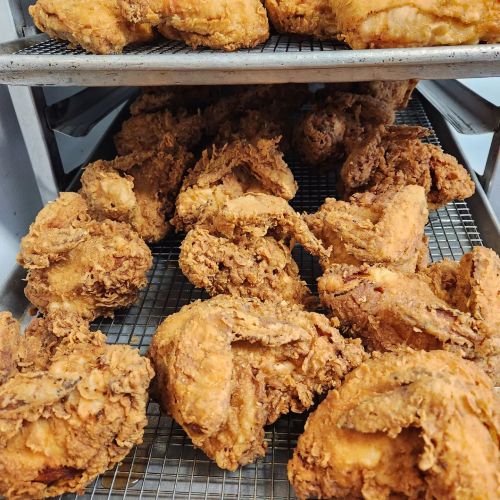 A close-up of golden-brown fried chicken pieces arranged on a wire rack.