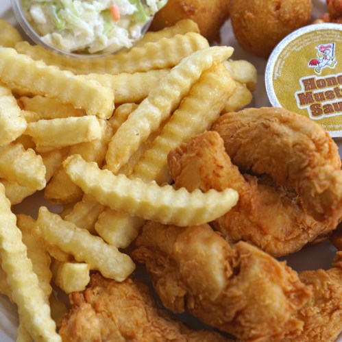 A plate of golden fried shrimp, crinkle-cut fries, hush puppies, coleslaw, and a cup of honey mustard sauce.