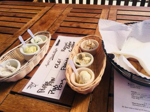 A wooden table with baskets of ice cream samples and a menu, alongside a basket of napkins.