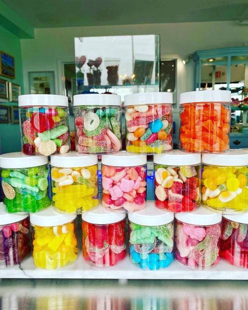 A colorful display of jars filled with various candies, arranged neatly on a shelf.