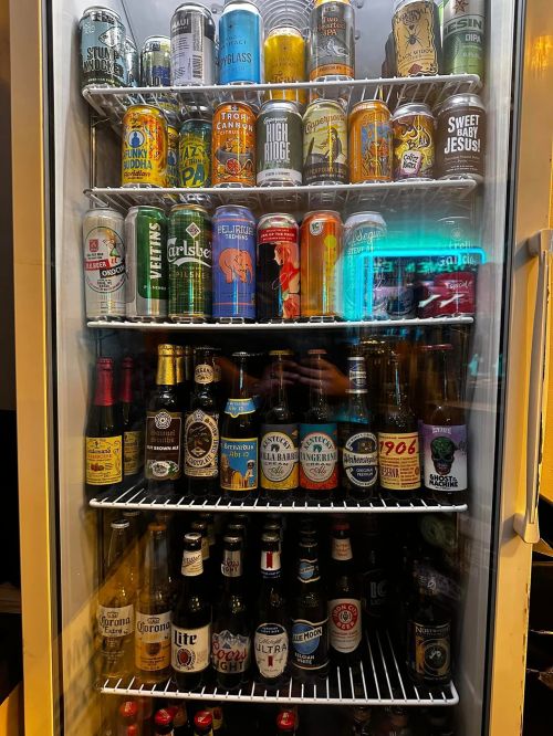 A refrigerator filled with various beer cans and bottles, showcasing a colorful assortment of brands and styles.