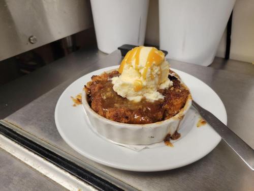 A warm dessert in a ramekin topped with vanilla ice cream and drizzled with caramel sauce.