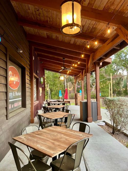A rustic outdoor dining area with wooden tables, string lights, and a cozy atmosphere.