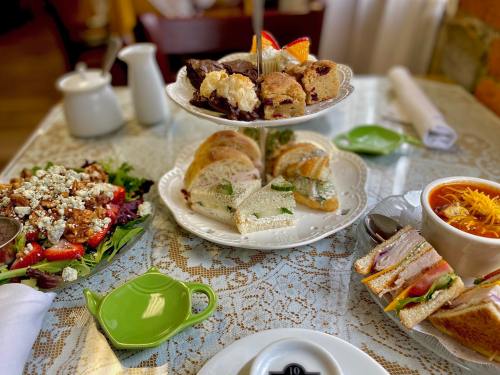 A table set with a tiered stand of pastries, sandwiches, a salad, and a bowl of soup, all elegantly arranged.