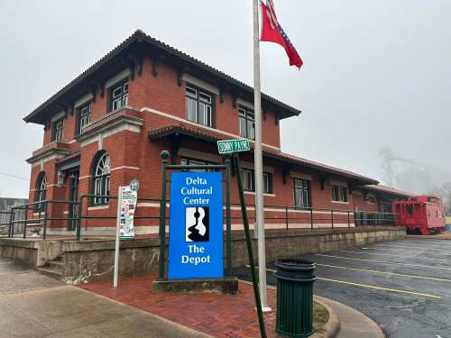 A brick building with a sign for the Delta Cultural Center, surrounded by fog and a street sign for Sonny Payne.