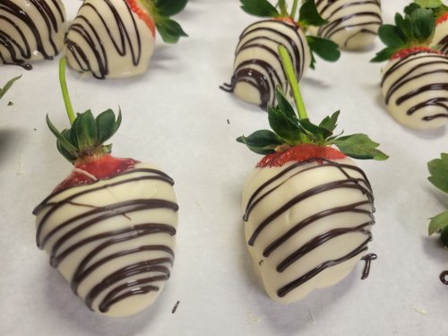White chocolate-covered strawberries drizzled with dark chocolate, arranged on parchment paper.