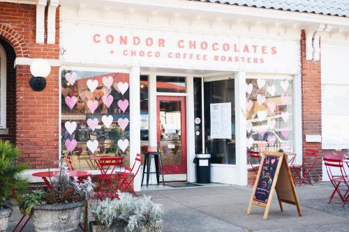 Exterior of Condor Chocolates with heart decorations on the windows and red outdoor seating.