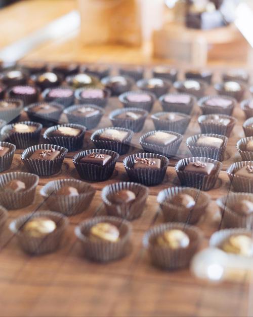A variety of chocolates arranged neatly in small paper cups on a wooden surface.