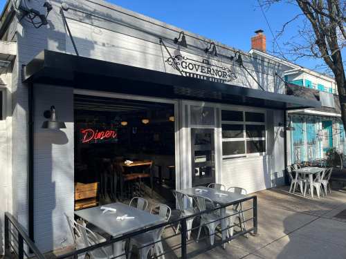 Exterior of Governors Diner, featuring a sign and outdoor seating under a clear blue sky.