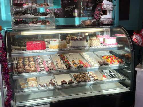 A display case filled with various colorful cakes, pastries, and desserts, showcasing an array of sweet treats.
