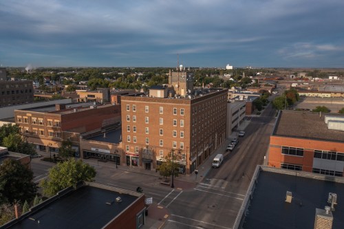 Aerial view of a cityscape featuring buildings, streets, and a cloudy sky.