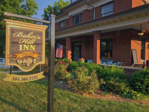A charming brick inn with a sign reading "Baker's Hill Inn, circa 1910," surrounded by greenery and an American flag.
