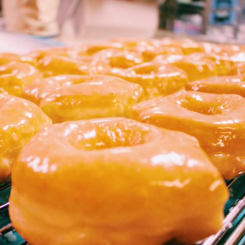 Close-up of freshly glazed donuts on a cooling rack, glistening with a shiny, sweet glaze.