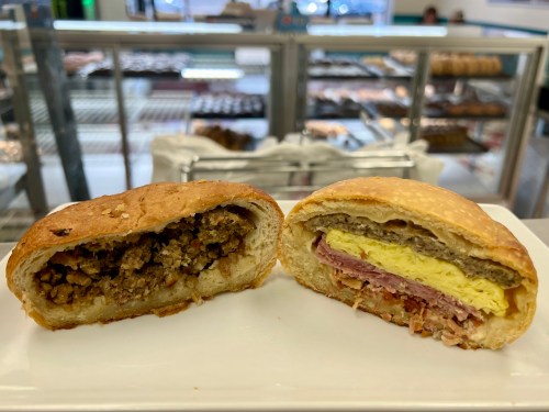 A split view of two sandwiches on a plate: one with sausage and stuffing, the other with ham and egg.