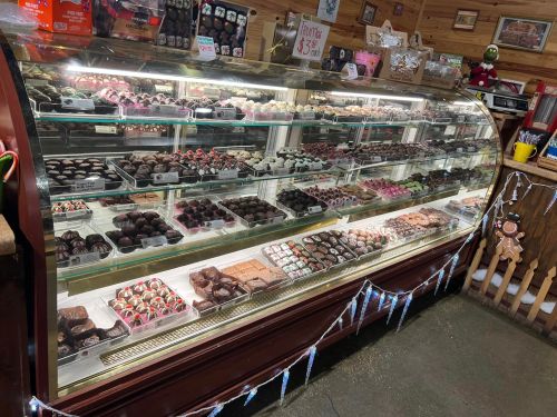 A display case filled with various chocolates and desserts, showcasing an array of colorful treats and confections.