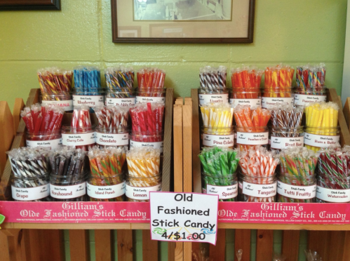 A display of colorful old-fashioned stick candies in clear bags, labeled with various flavors and prices.