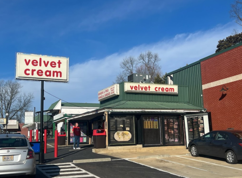 A storefront with a green roof and red signage reading "velvet cream," set against a clear blue sky.