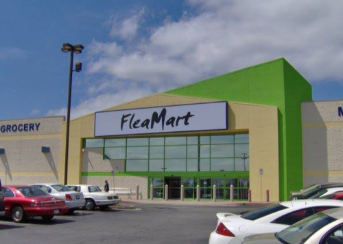 Exterior of a store named "FleaMart," featuring a bright green facade and parked cars in front.