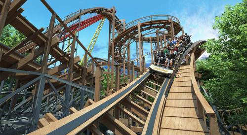 A wooden roller coaster with riders descending a steep track surrounded by trees and blue skies.