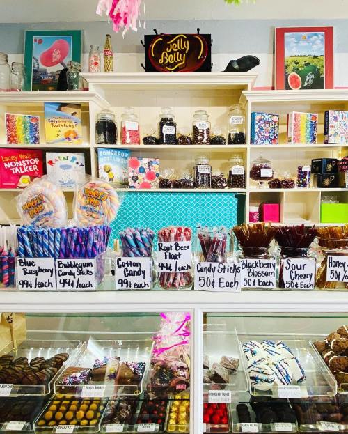 A colorful candy shop display featuring various candies, including Jelly Belly, cotton candy, and chocolate treats.