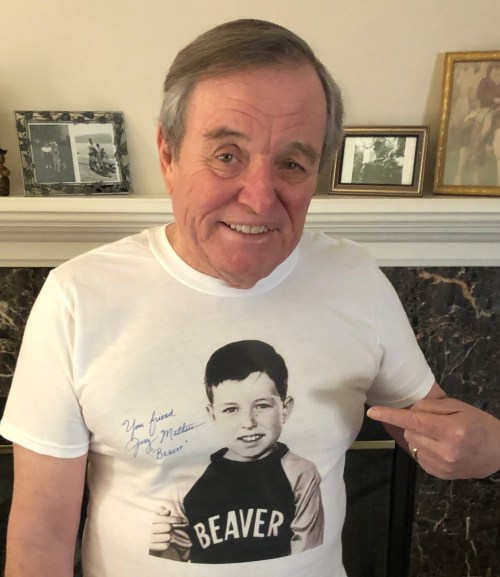 Smiling man in a white t-shirt with a vintage photo of a boy and the text "You fired Jim Matthews, Beaver."