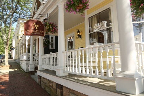 Charming bed and breakfast with a welcoming porch, colorful flowers, and a sign reading "The Almondy."
