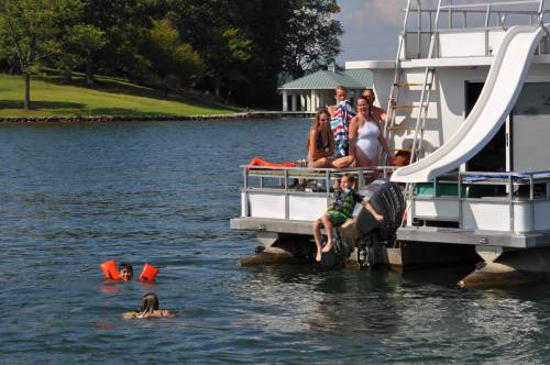 A group of people on a houseboat, with some swimming nearby and others relaxing on the deck.
