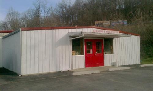 Exterior of Abruzino's Italian Bakery, featuring a white metal building with red doors and a sign above.