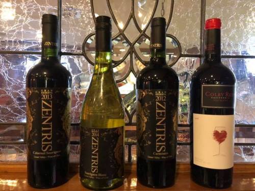 Four wine bottles displayed on a wooden shelf, featuring Zentris Cabernet Sauvignon, Zentris Sauvignon Blanc, and Colby Red.