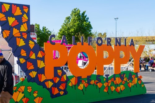 Colorful sign for the California Poppy Festival, featuring poppy flowers and a map outline of California.