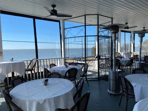 A bright, airy restaurant with white tables and a view of the ocean through large windows.