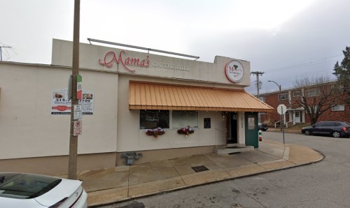 Exterior of Mama's on the Hill restaurant, featuring an orange awning and flower boxes, on a cloudy day.