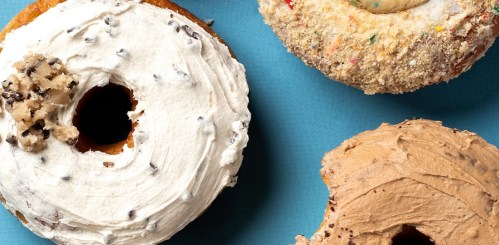 Three colorful donuts with various toppings: white frosting with chocolate chips, sprinkles, and a chocolate cream finish.