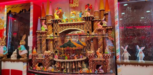 A colorful gingerbread castle with candy decorations, bunnies, and a carousel, set in a festive display.