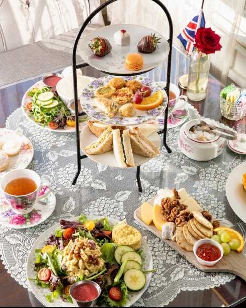 A beautifully arranged afternoon tea spread with sandwiches, salads, pastries, and a pot of tea on a lace tablecloth.