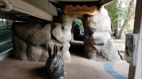 A stone archway labeled "Underland" with a large rabbit sculpture in front, set in a playful outdoor area.